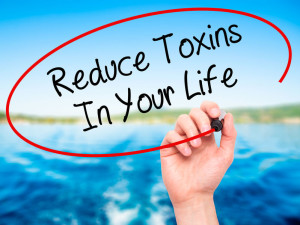 Man Hand writing Reduce Toxins In Your Life with black marker on